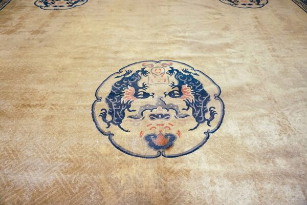 Low-pile beige rug featuring a circular dark blue, orange, and gray stylized creature motif.