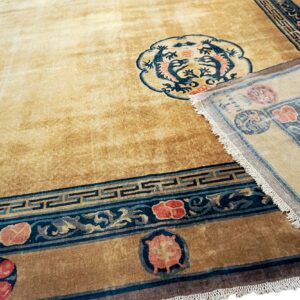 Camel rug featuring a blue dragon medallion and red floral motifs; a corner is folded back.