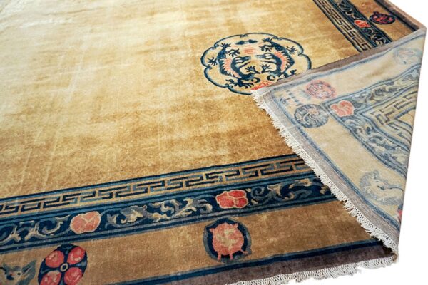 Camel rug featuring a blue dragon medallion and red floral motifs; a corner is folded back.