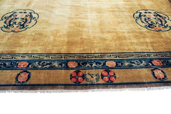 Gold rug featuring twin blue dragon medallions and complex borders with red floral and dark blue geometric patterns.