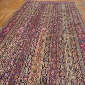 Long rug with alternating stripes of geometric and paisley patterns rests on light wood floors.