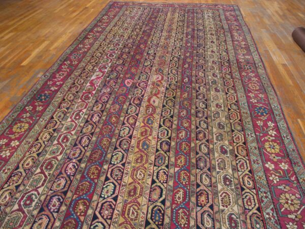 Long rug with alternating stripes of geometric and paisley patterns rests on light wood floors.
