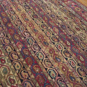 Rug with colorful red, gold, and navy vertical stripes of intricate paisley and geometric designs on a wood floor.