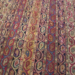 A detailed rug view shows vertical stripes of red, yellow, navy, and beige geometric motifs.