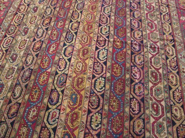 A detailed rug view shows vertical stripes of red, yellow, navy, and beige geometric motifs.