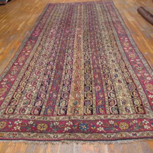 Long traditional rug featuring striped red and navy geometric patterns on a glossy hardwood floor.