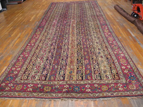 Long traditional rug featuring striped red and navy geometric patterns on a glossy hardwood floor.