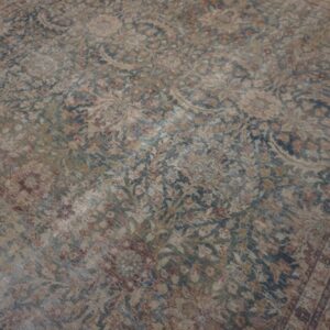 Distressed, low-pile rug displaying a faded traditional floral pattern in muted blue, tan, and red.