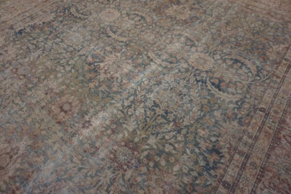 Distressed, low-pile rug displaying a faded traditional floral pattern in muted blue, tan, and red.
