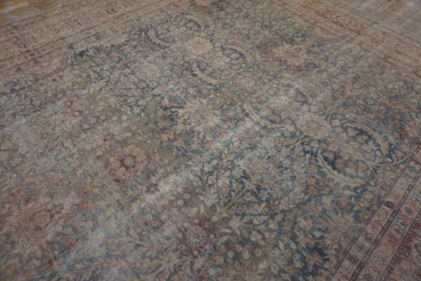 Faded traditional rug in beige, blue, and maroon laying on a light wooden floor.