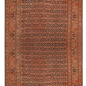 A dense floral rug, primarily dark blue and rust, with a wide, scrolling tan border pattern.