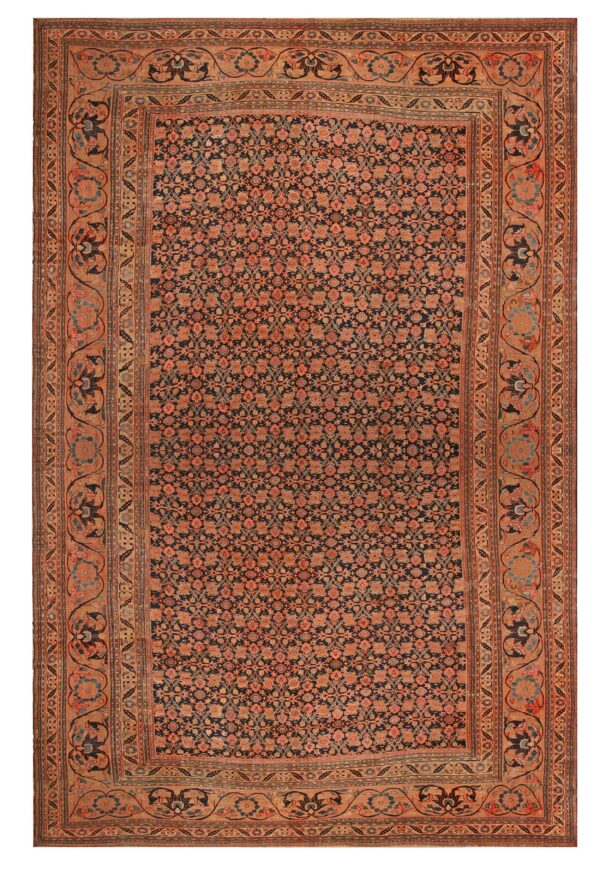 A dense floral rug, primarily dark blue and rust, with a wide, scrolling tan border pattern.