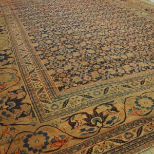 Large rug with dense rust and gold floral motifs on an indigo field and wide tan border.
