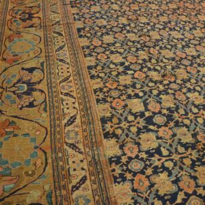 Intricate rug featuring a navy floral field, coral and gold motifs, and a wide ochre botanical border.