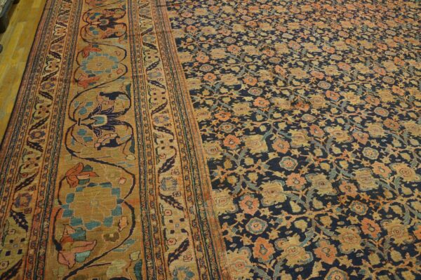 Intricate rug featuring a navy floral field, coral and gold motifs, and a wide ochre botanical border.