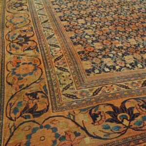Low-pile rug with a navy floral field, rust-colored main border, and intricate details on wood flooring.