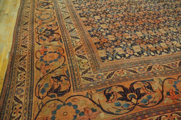 Low-pile rug with a navy floral field, rust-colored main border, and intricate details on wood flooring.