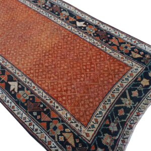 Rustic orange rug with an allover geometric field framed by a bold navy and multi-colored border.
