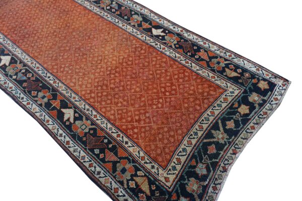 Rustic orange rug with an allover geometric field framed by a bold navy and multi-colored border.