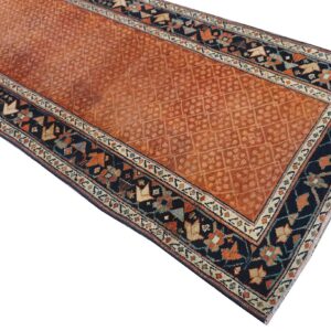 Rust orange runner rug with a repeating lattice field pattern and detailed navy blue geometric borders.