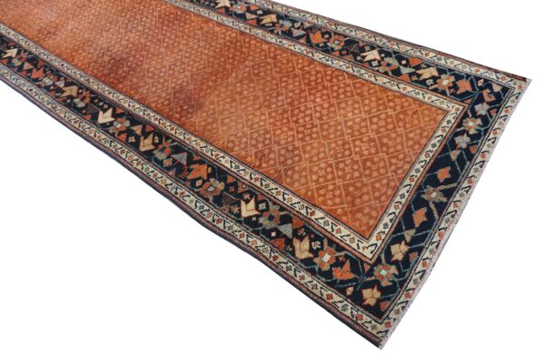 Rust orange runner rug with a repeating lattice field pattern and detailed navy blue geometric borders.