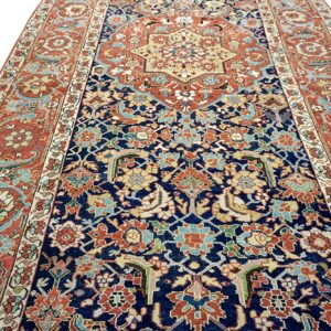 Intricate traditional rug with a navy blue field, rust-orange borders, and a multicolored central medallion.