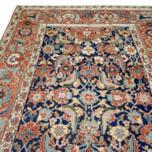 Low-pile rug featuring complex traditional motifs in navy, rust, light blue, and cream colors.