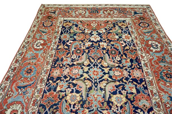 Low-pile rug featuring complex traditional motifs in navy, rust, light blue, and cream colors.