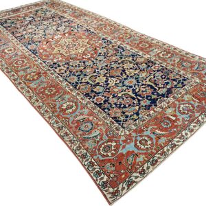 Ornate navy runner rug with a central medallion and broad rust red and light blue borders.