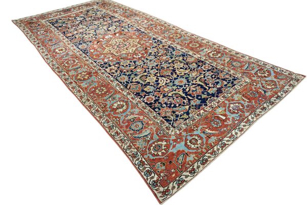 Ornate navy runner rug with a central medallion and broad rust red and light blue borders.