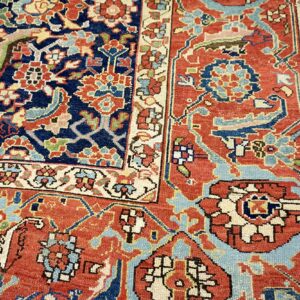 Traditional low-pile rug detail showing navy and rust fields with blue and cream intricate floral patterns.