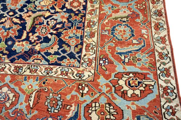Traditional low-pile rug detail showing navy and rust fields with blue and cream intricate floral patterns.