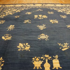 Navy blue rug with scattered pale yellow floral motifs and a detailed geometric border on wood flooring.