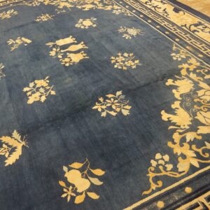Blue area rug with scattered yellow floral patterns and wide border motifs on wood planks.