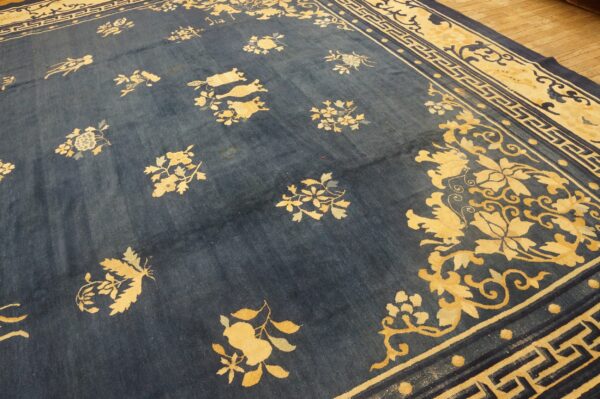 Blue area rug with scattered yellow floral patterns and wide border motifs on wood planks.