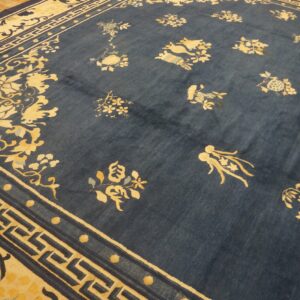 A richly patterned blue and cream rug featuring scattered florals and key borders on wood flooring.