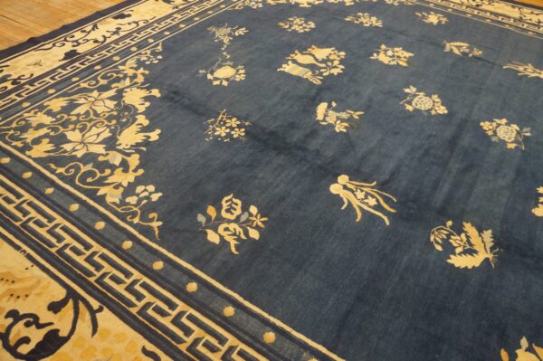 A richly patterned blue and cream rug featuring scattered florals and key borders on wood flooring.