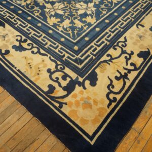 Blue and beige Oriental rug corner with floral and geometric borders on rough wooden planks.