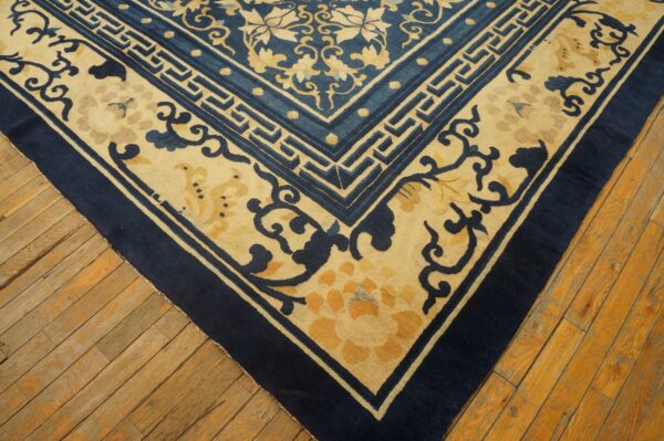 Blue and beige oriental rug corner with floral and geometric borders on rough wooden planks.