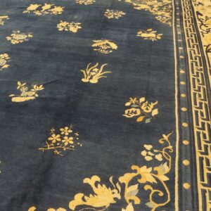 Dark blue rug featuring scattered yellow and blue floral motifs and a wide patterned yellow border on wood floor.