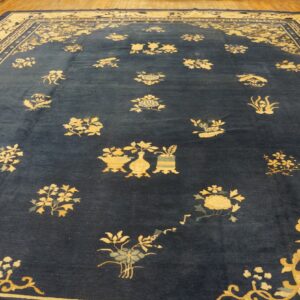 A deep blue area rug with contrasting golden scattered floral patterns and borders on a wooden floor.