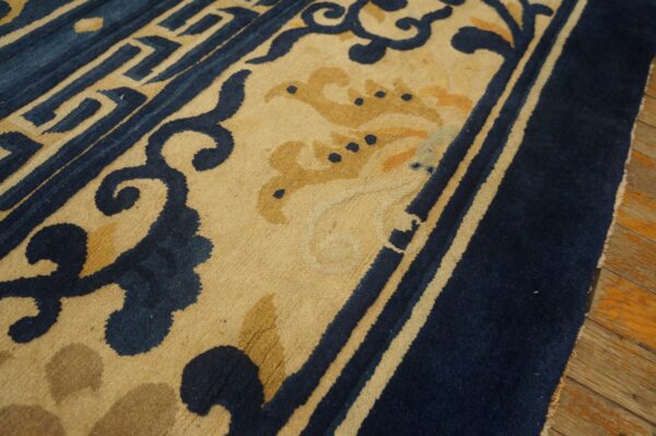 Textured navy blue and cream rug featuring scroll and geometric patterns on a distressed wood floor.
