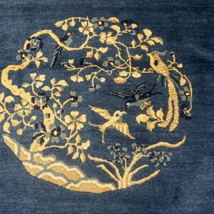 Navy blue rug featuring a circular golden floral and bird medallion with blue and gray accents.