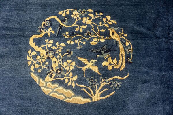 Navy blue rug featuring a circular golden floral and bird medallion with blue and gray accents.