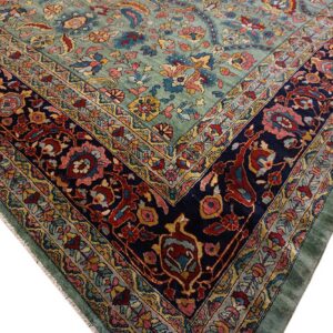 Ornate floral rug corner with a light blue-green field and a complex navy border with red and gold details.