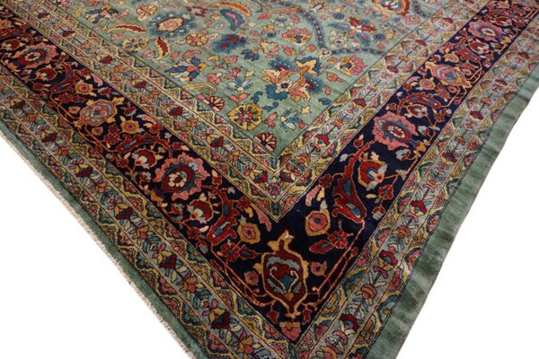 Ornate floral rug corner with a light blue-green field and a complex navy border with red and gold details.