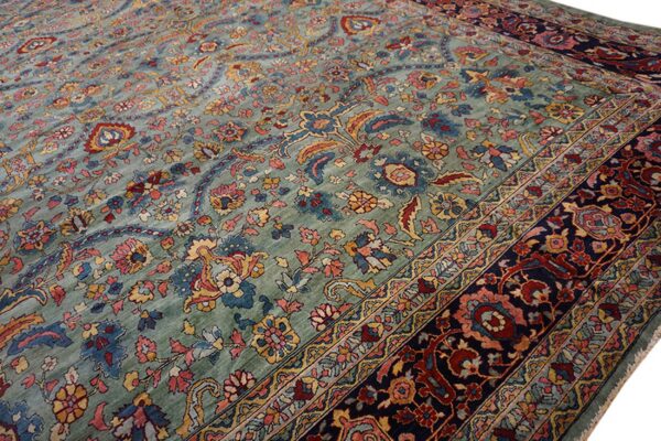 Ornate sage rug with a high pile, featuring red, gold, and blue traditional floral patterns and a navy border.