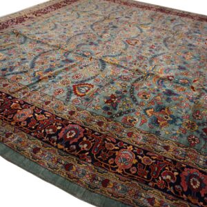 Low-pile rug with a teal field, featuring intricate red, blue, and gold floral patterns and a wide dark border.
