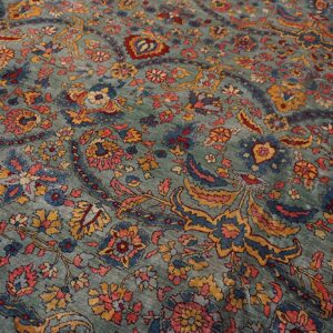 Muted seafoam rug featuring traditional scrolling floral and paisley patterns in coral, blue, and gold.