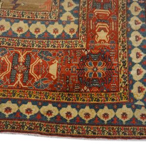Intricate rug border detail showing red, blue, and gold geometric patterns and stylized floral motifs.